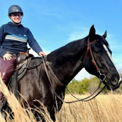 Person riding a horse with a western saddle from a side angle using the brown Correct Connect Double Neck Strap.